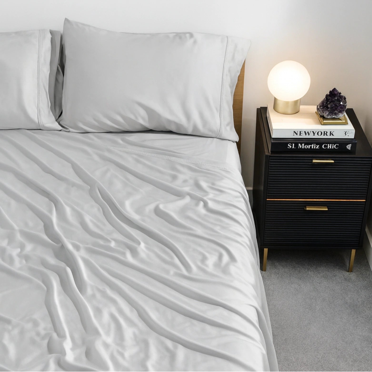 Light grey eucalyptus-infused bamboo sheets styled beside lamp and nightstand. Luxury eco-friendly bedding creating a fresh, breathable sleep environment.