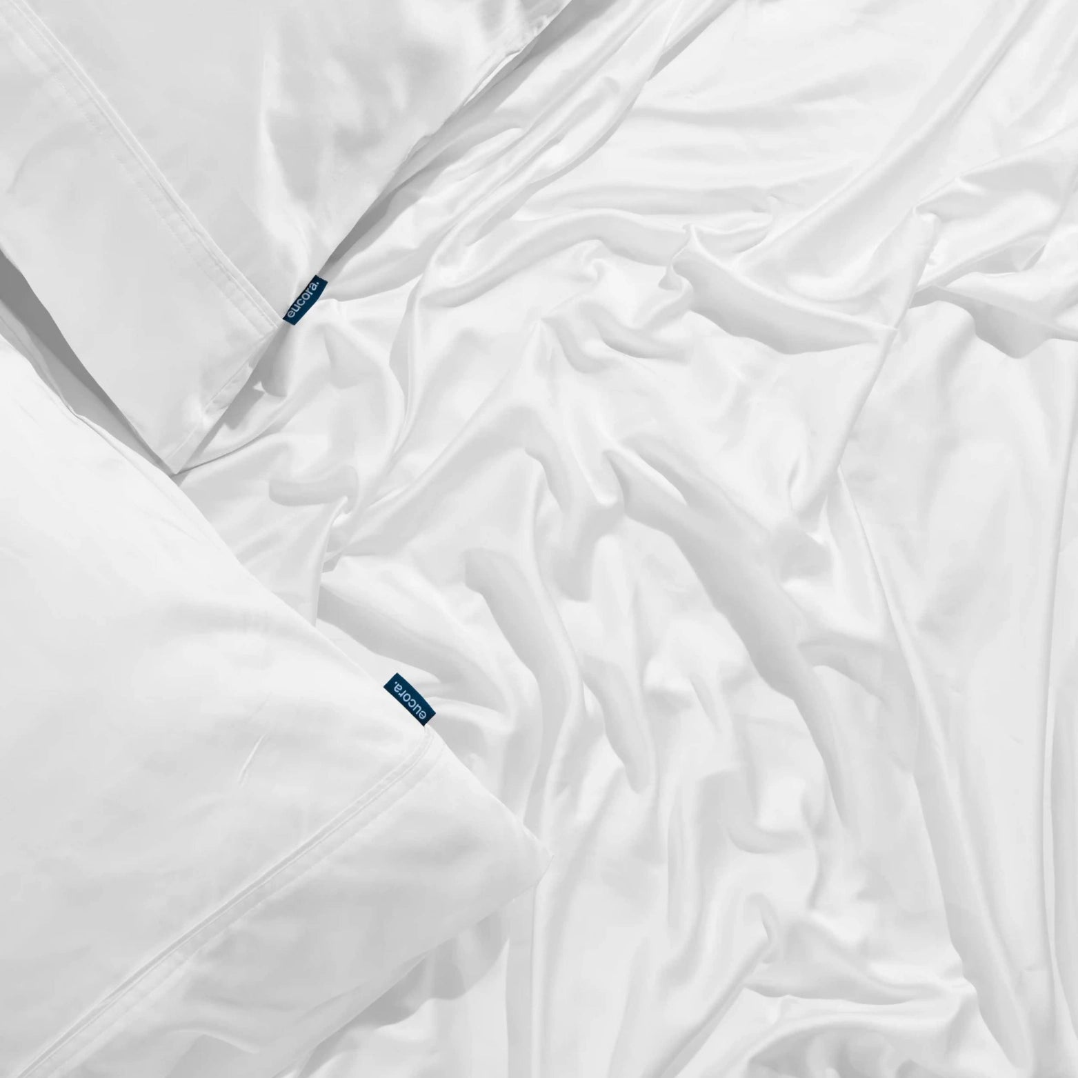 Close-up of Eucora bamboo sheet label on soft white fabric. Eco-certified, OEKO-TEX bamboo bedding for luxury and durability in every detail